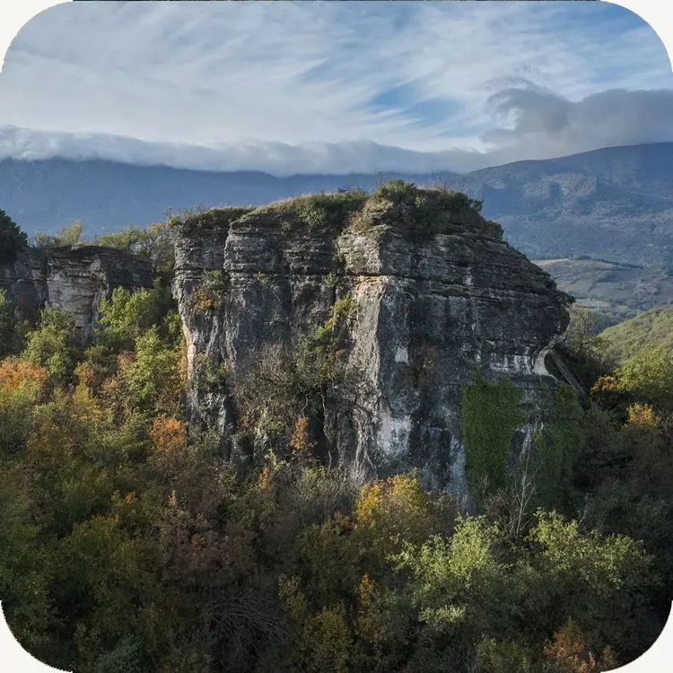 Uno dei torrioni dei Luchi svetta sul bosco autunnale con il Monte Morrone sullo sfondo